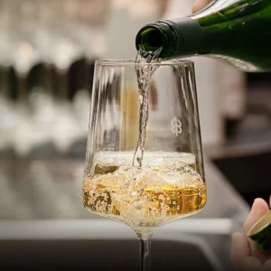 Ein Weißweinglas, welches aus einer Flasche befüllt wird